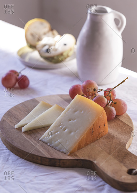 High angle of various palatable cheese arranged on table with Anona fruits and grapes near ceramic jug