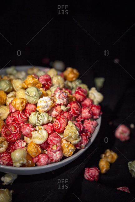 Tasty colorful popcorn in bowl placed on black background in studio