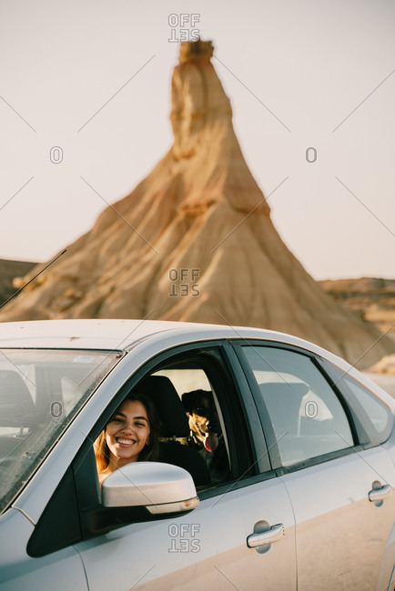 Delighted female traveler sitting in automobile in Bardenas Reales during vacation in Spain and looking at camera