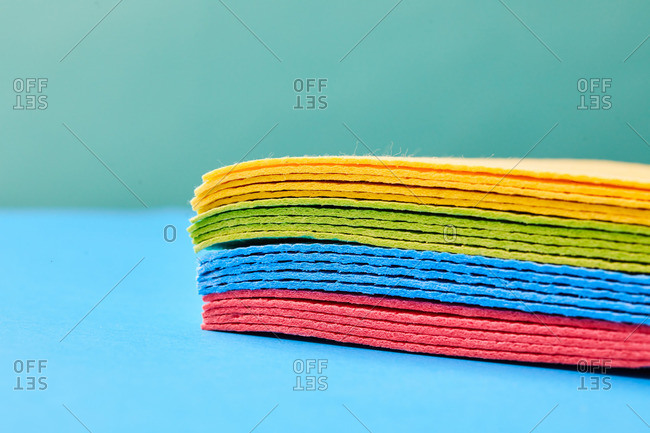 Closeup of heap of multicolored rags placed on blue background in studio demonstrating concept of cleaning and housework