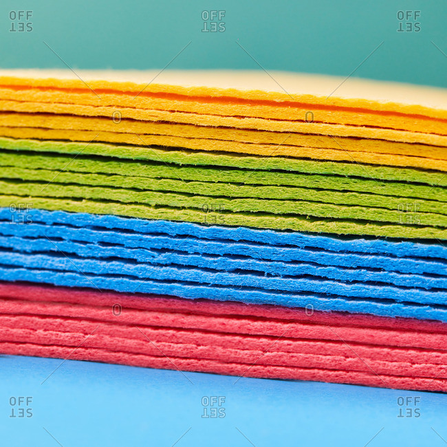 Closeup of heap of multicolored rags placed on blue background in studio demonstrating concept of cleaning and housework