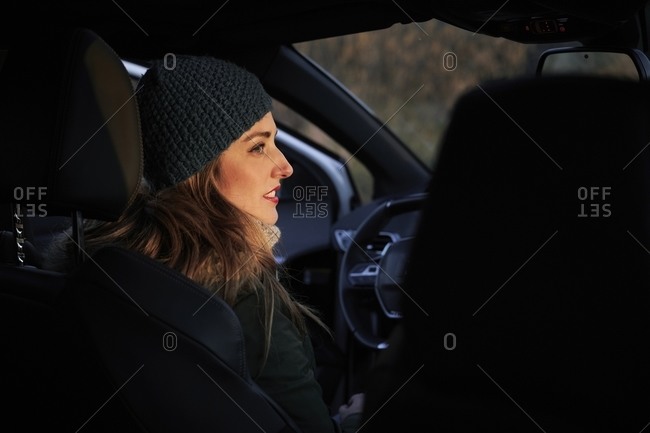 Female traveler sitting on driver seat during road trip along roadway in highlands in cold season