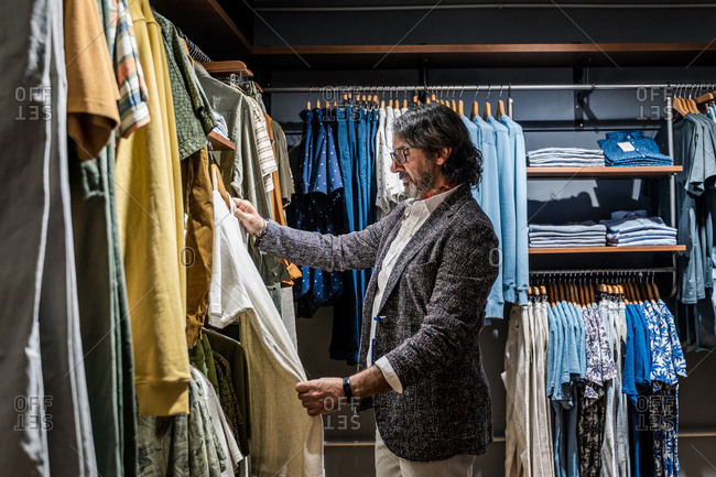 Side view of man choosing clothes in a clothing store