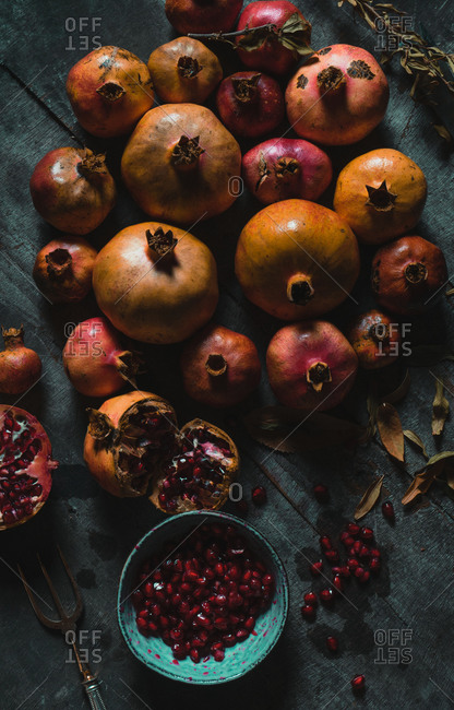 Top view of pile of colorful fresh pomegranates arranged on table with dried plants