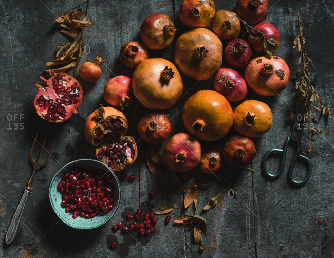 Top view of pile of colorful fresh pomegranates arranged on table with dried plants