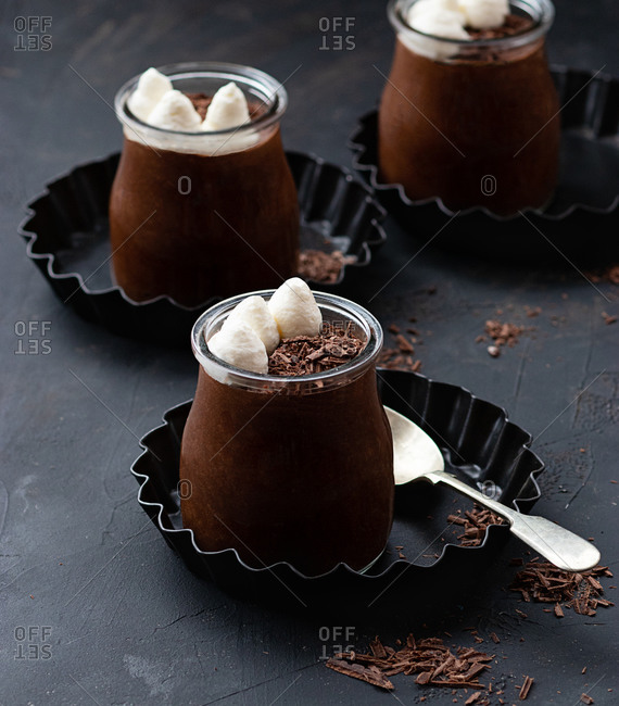 Tasty chocolate mousse in glass jar arranged on table with chocolate powder dust