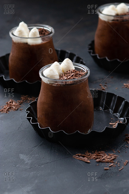 Tasty chocolate mousse in glass jar arranged on table with chocolate powder dust
