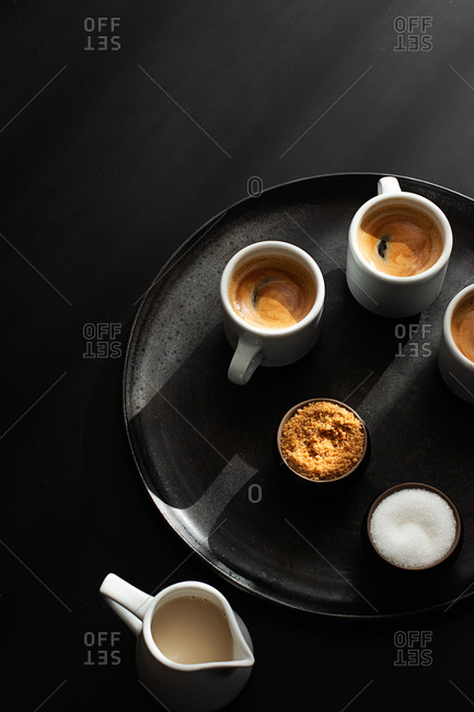 Cups of coffee served on a tray on dark background