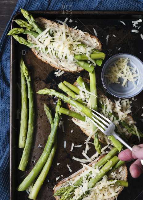 Asparagus spears and grated cheese on sourdough bread.