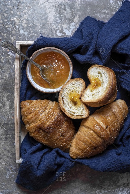 Wood tray with fresh brioche croissants served with jam