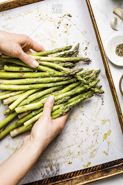 Person tossing asparagus to make sure it is seasoned well