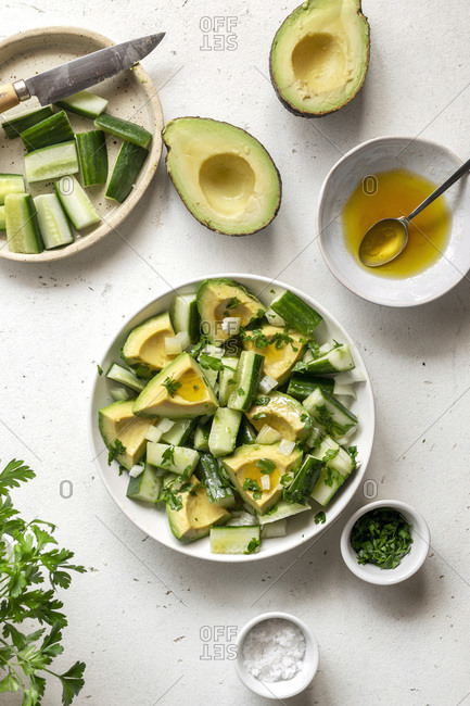 Avocado and cucumber salad in a bowl over white background
