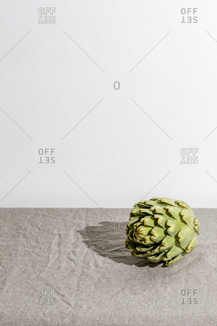 Artichoke on the table covered with a gray linen tablecloth