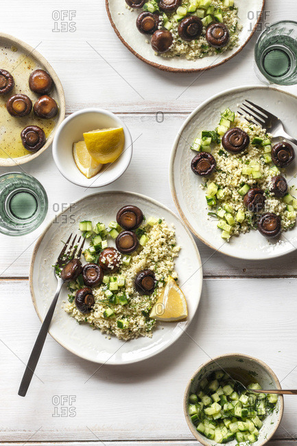 Couscous salad with roasted mushrooms and cucumber on white background