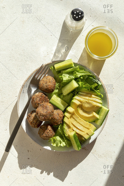 Vegetarian meatballs with lettuce, cucumber and avocado salad in a bowl
