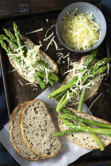 Asparagus and grated cheese on sourdough bread with grains and seeds.