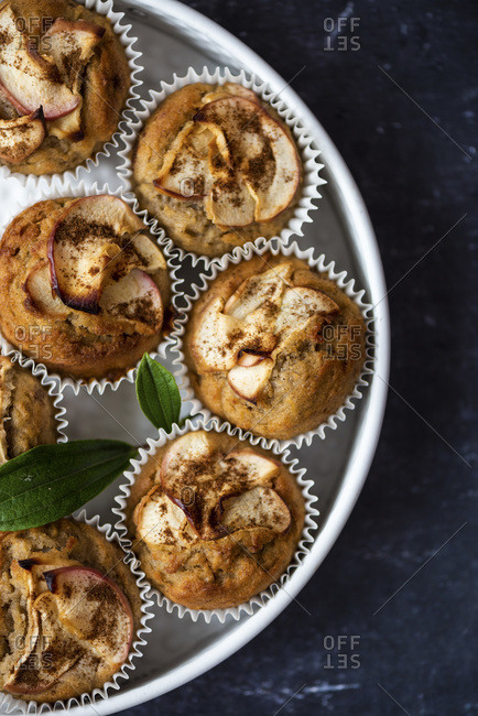 Apple cinnamon muffins in a white pan on a dark background.