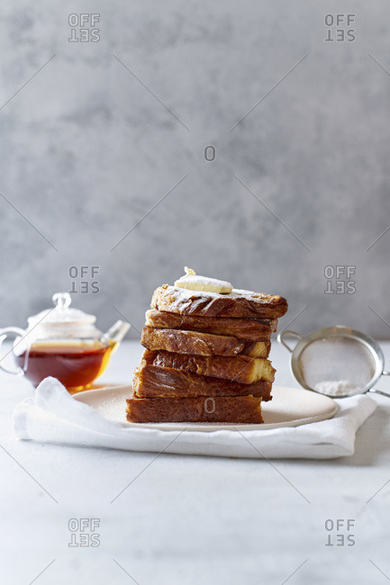 A pile of French toasts for breakfast with butter and powdered sugar side view