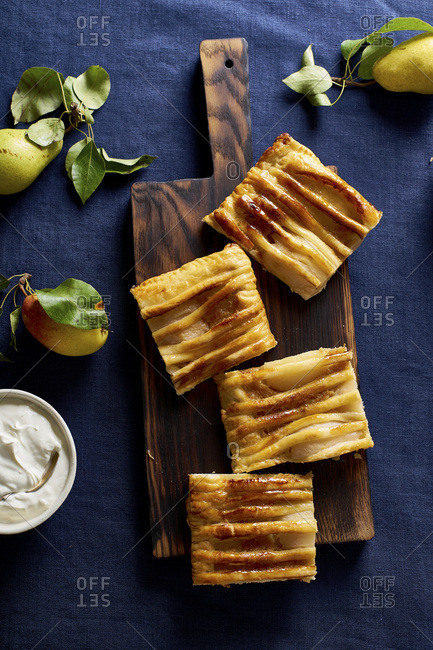 Sliced dartois with pears - French puff pastry tart with fruits and frangipane on dark blue background