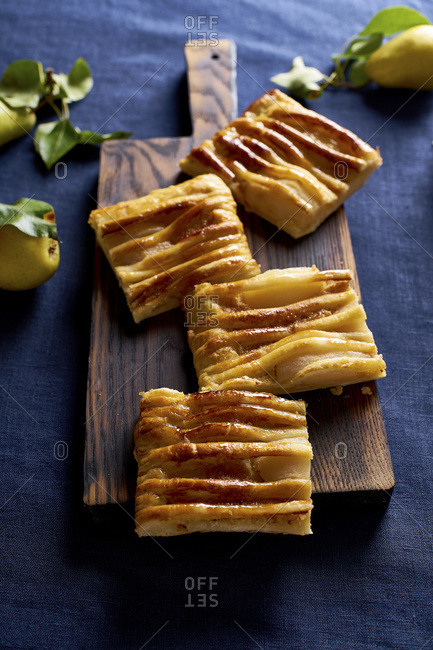 Sliced dartois with pears - French puff pastry tart with fruits and frangipane on dark blue background