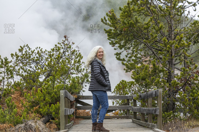 USA, Wyoming, Yellowstone National Park, Senior female tourist standing on wooden observation point in Yellowstone National Park