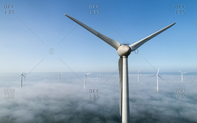 Offshore wind turbines standing in fog on the IJsselmeer inland sea, land based turbines in the clear, Flevoland, Netherlands