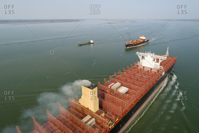 A 400m long container ship sails to the port of Antwerp, passing smaller ships. The ship not fully loaded, due to coronavirus