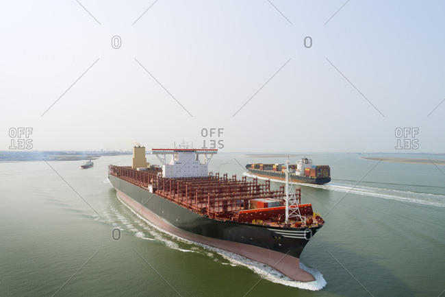 A 400m long container ship sails to the port of Antwerp, passing smaller ships. The ship not fully loaded, due to coronavirus