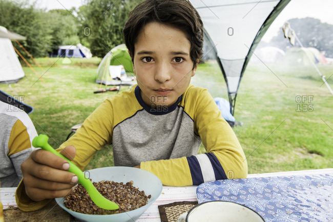 Boy eating breakfast at camp site