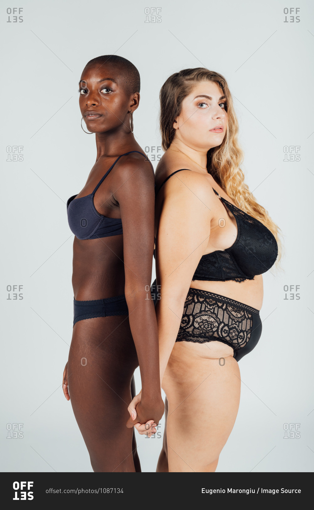 Female couple, standing back to back in underwear stock photo - OFFSET
