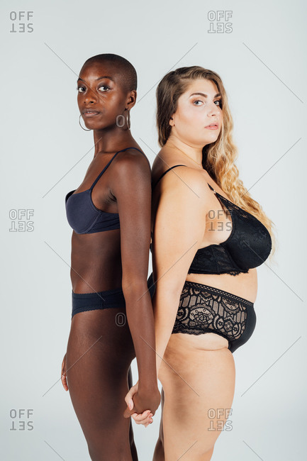 Two women in sexy underwear standing backwards and touching each other  Stock Photo by YouraPechkin