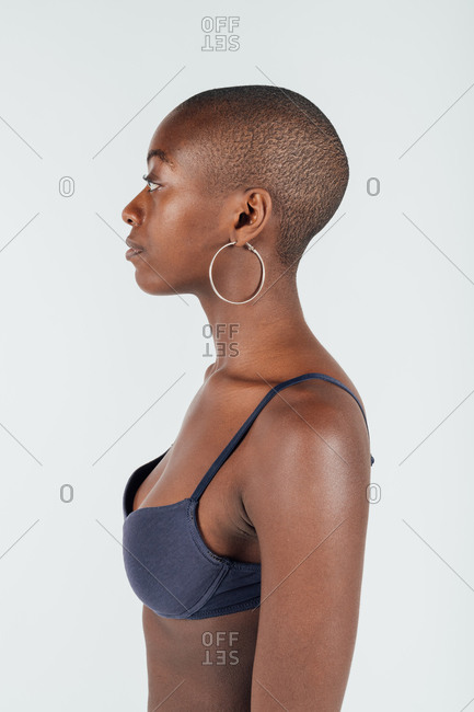Portrait of a young woman with shaved head, wearing bra stock photo - OFFSET