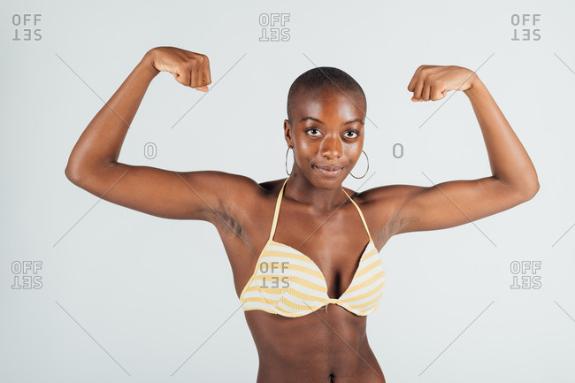 Young woman wearing bikini, flexing muscles