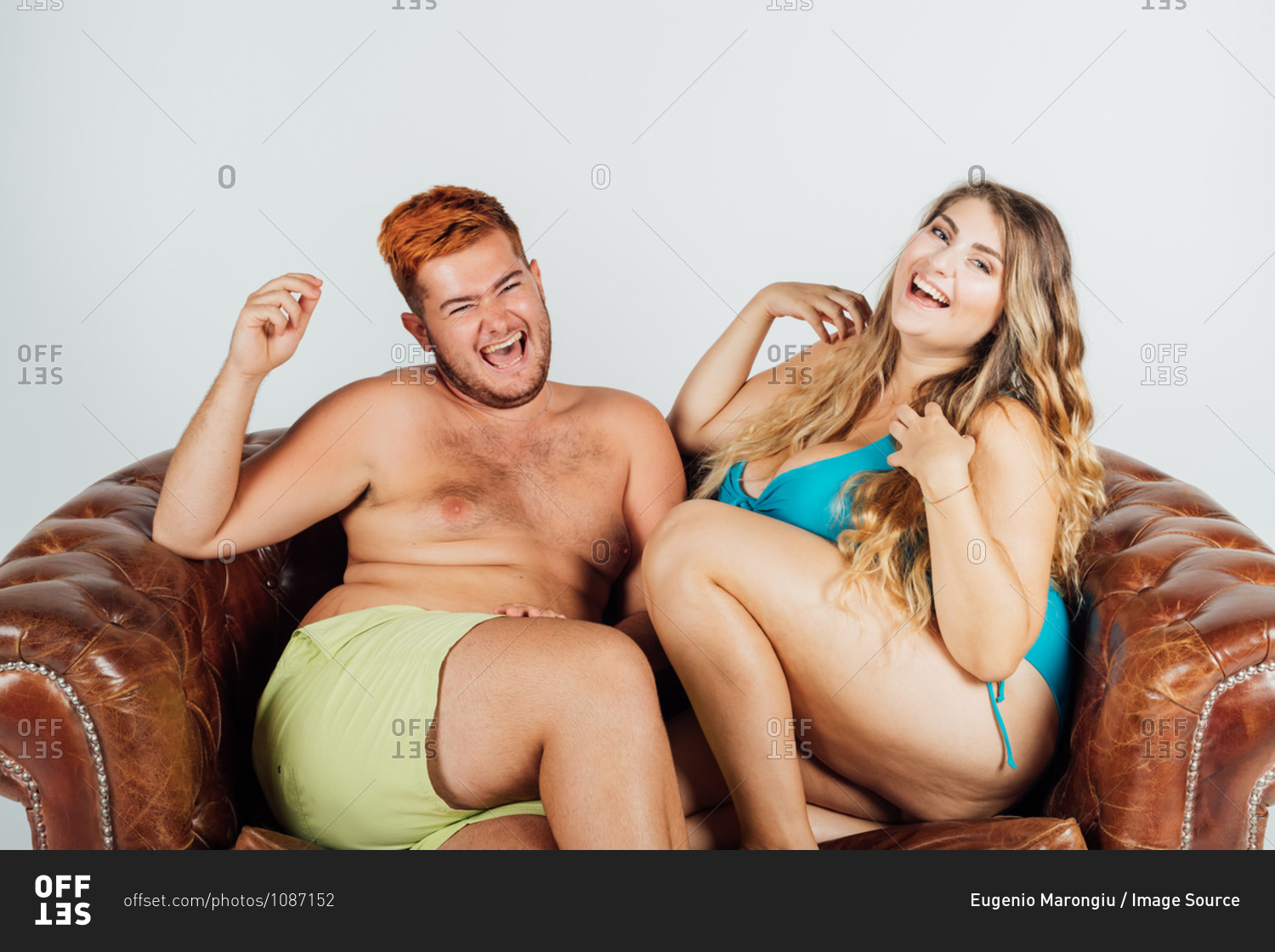 Young man and woman laughing, on sofa, partially clothed