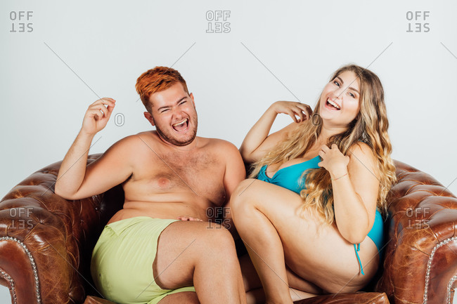 Young man and woman laughing, on sofa, partially clothed