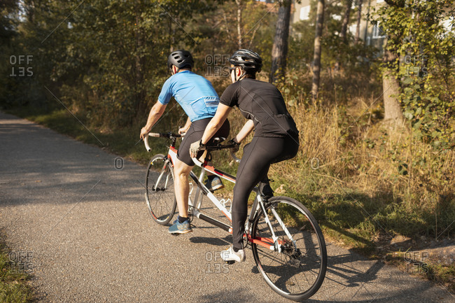 Visually impaired female triathlete training on tandem bicycle with her guide and coach