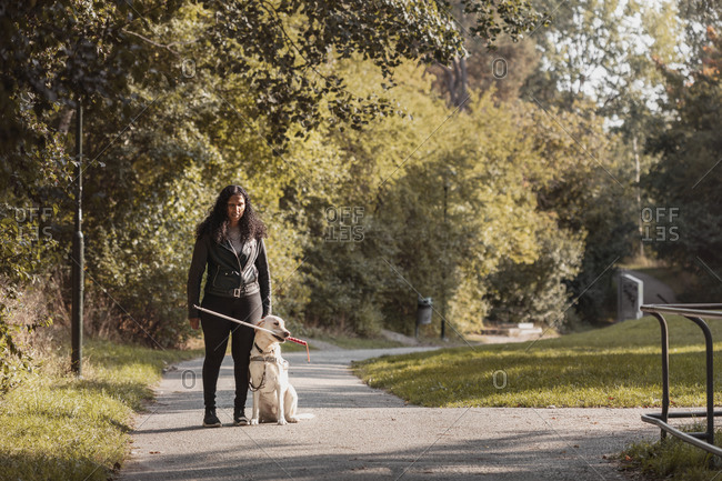 Visually impaired woman standing in park with guide dog