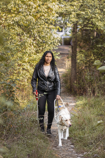 Visually impaired woman walking through park with guide dog
