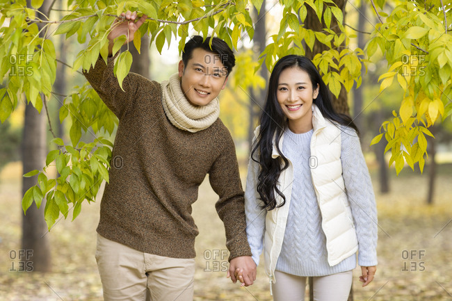 Happy young couple holding hands in woods