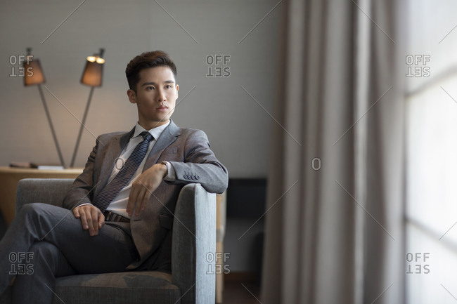 Young businessman sitting on sofa in hotel room