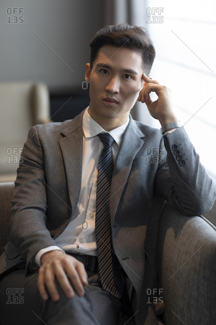 Young businessman sitting on sofa in hotel room