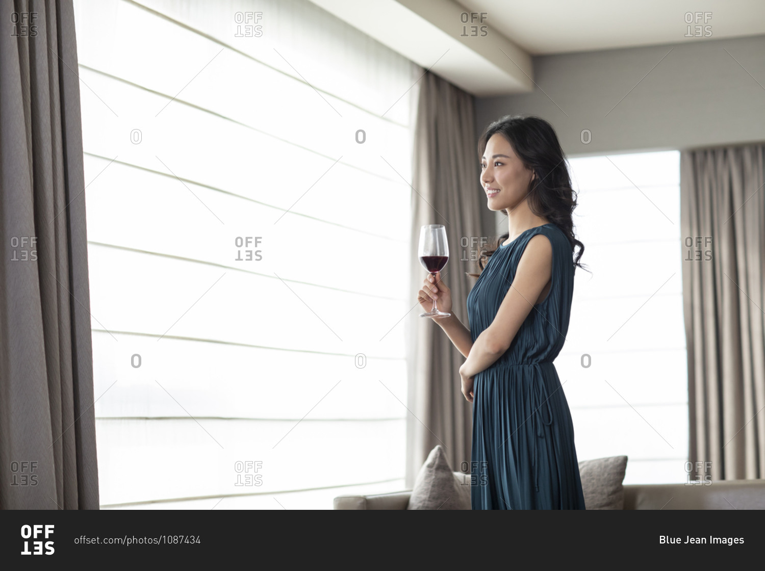 Happy young woman drinking wine in living room