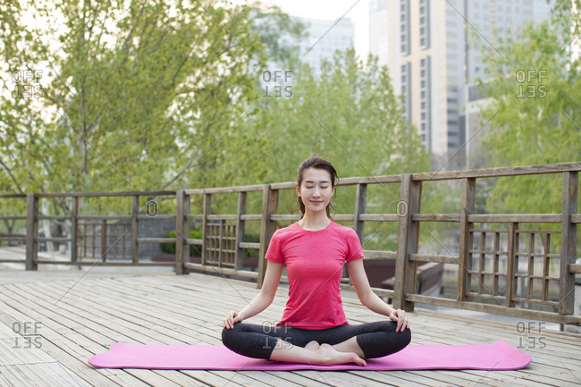 Happy young woman doing yoga in park