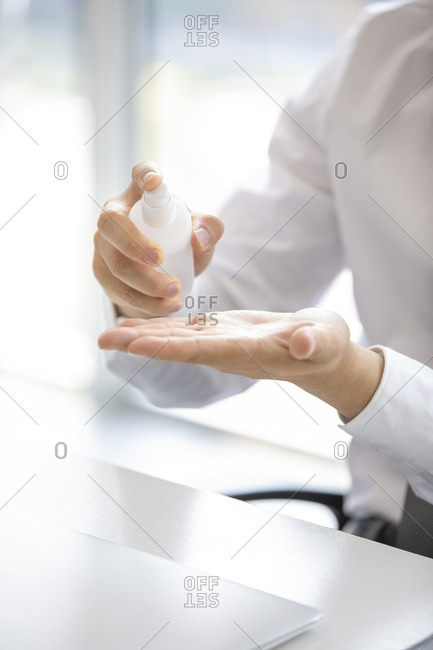 Young businessman using hand sanitizer in office