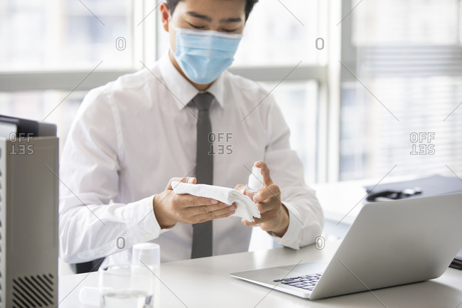 Young businessman using disinfectant in office