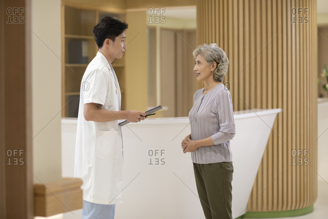Doctor talking to senior woman in hospital corridor