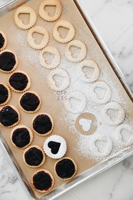 Heart Linzer cookies with powdered sugar being prepared on baking tray