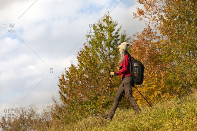 Female hiker with backpack and hiking pole walking on mountain at Alpine Foothills- Germany