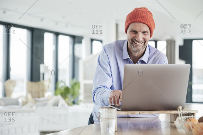 Businessman wearing knit hat working on laptop while sitting at home