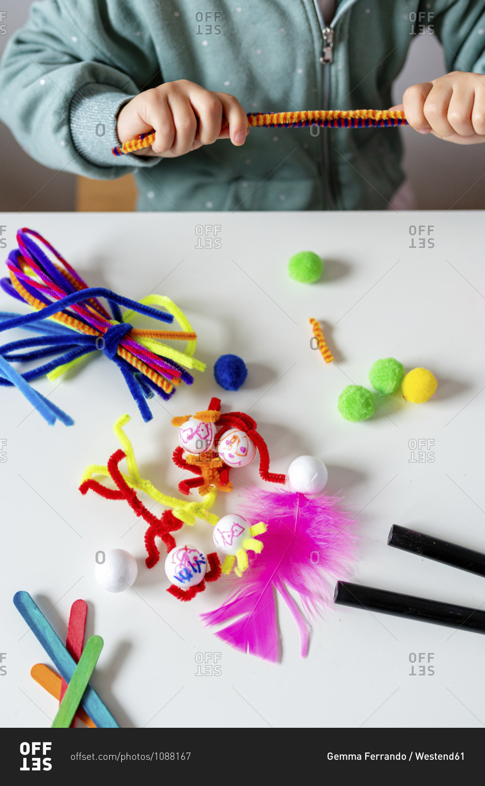 Girl holding pipe cleaners at table